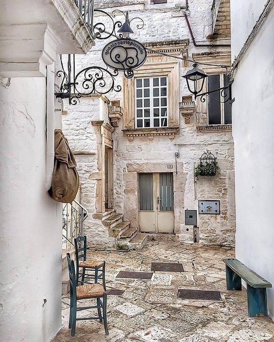 an alleyway with two chairs and a bench on the ground in front of a building