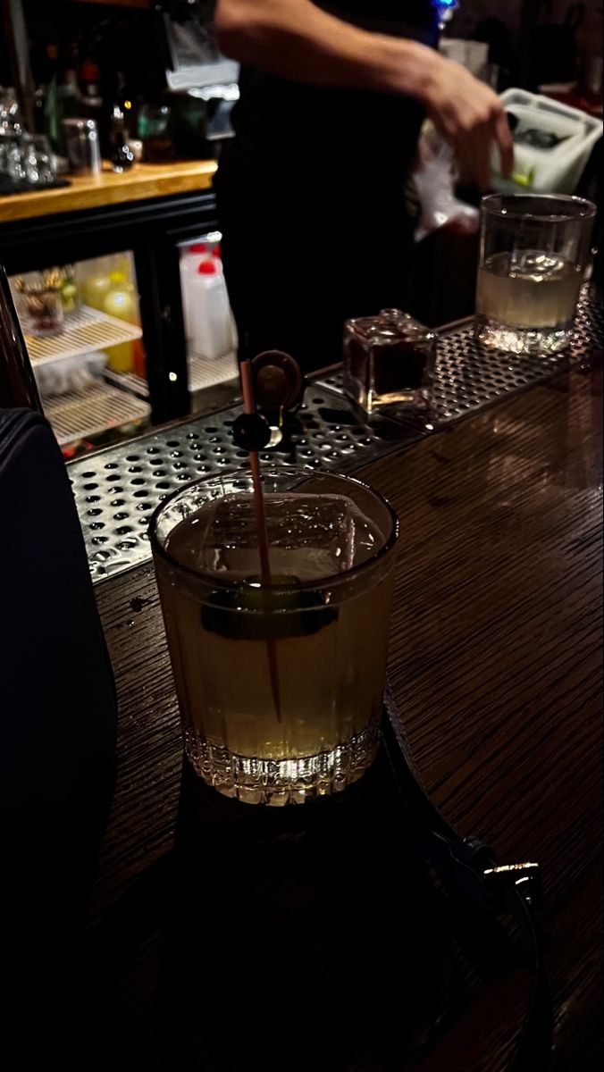 a bartender pours a drink into a glass on the bar at a restaurant,