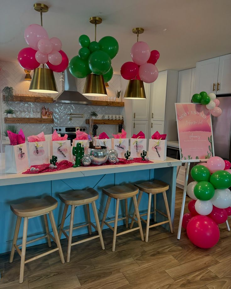 a kitchen decorated with balloons and pink, green, and white decorations for a baby's first birthday