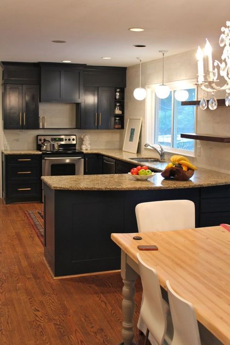 a kitchen with black cabinets and an island in the middle is seen from across the room