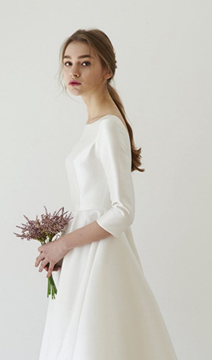 a woman in a white dress holding a bouquet of flowers