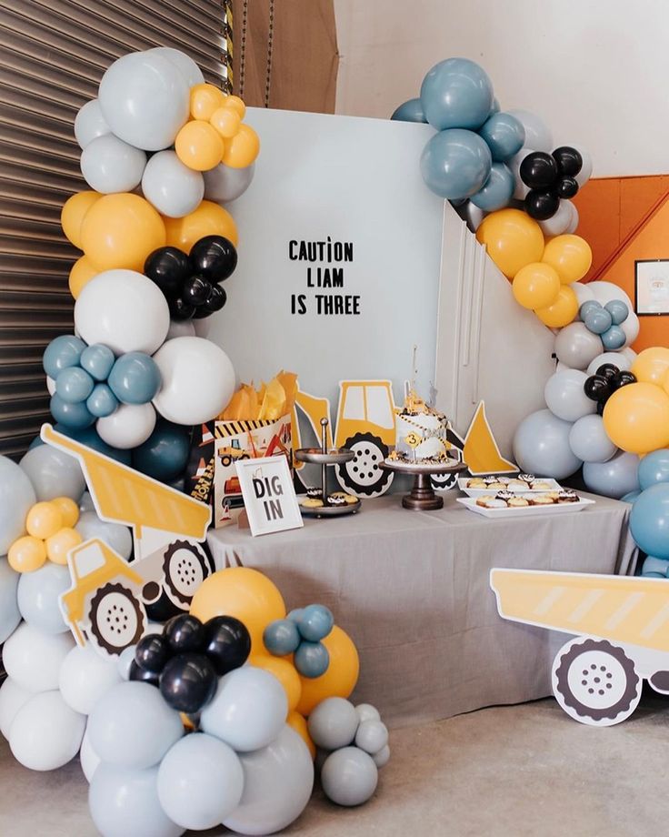 a table topped with balloons and construction themed decorations