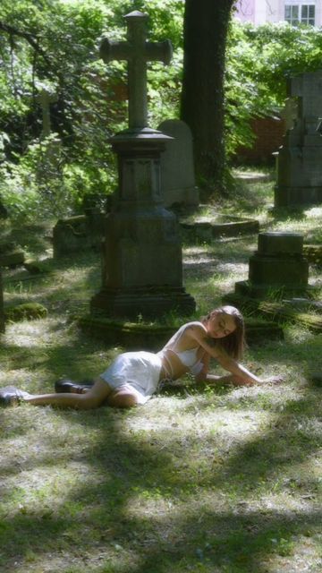 a woman laying on the ground in a cemetery