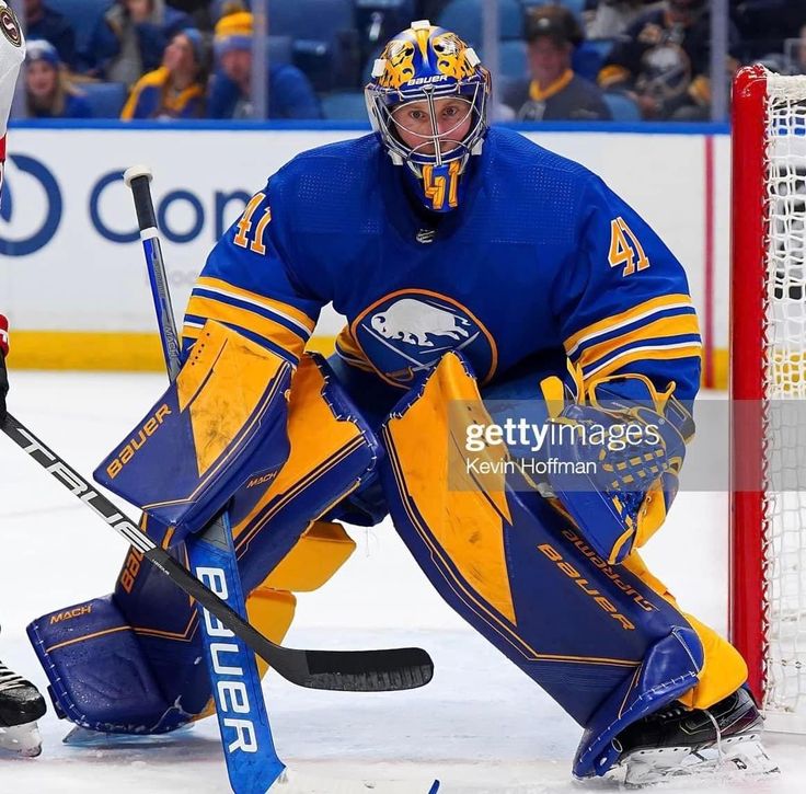 a hockey player squatting on the ice with his goalie's mitt in front of him