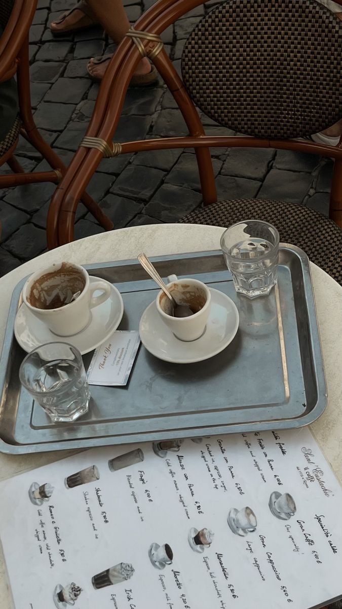 two cups of coffee are on a tray