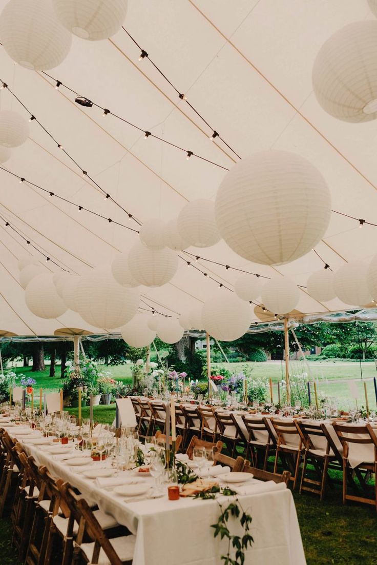 tables and chairs are set up under white paper lanterns