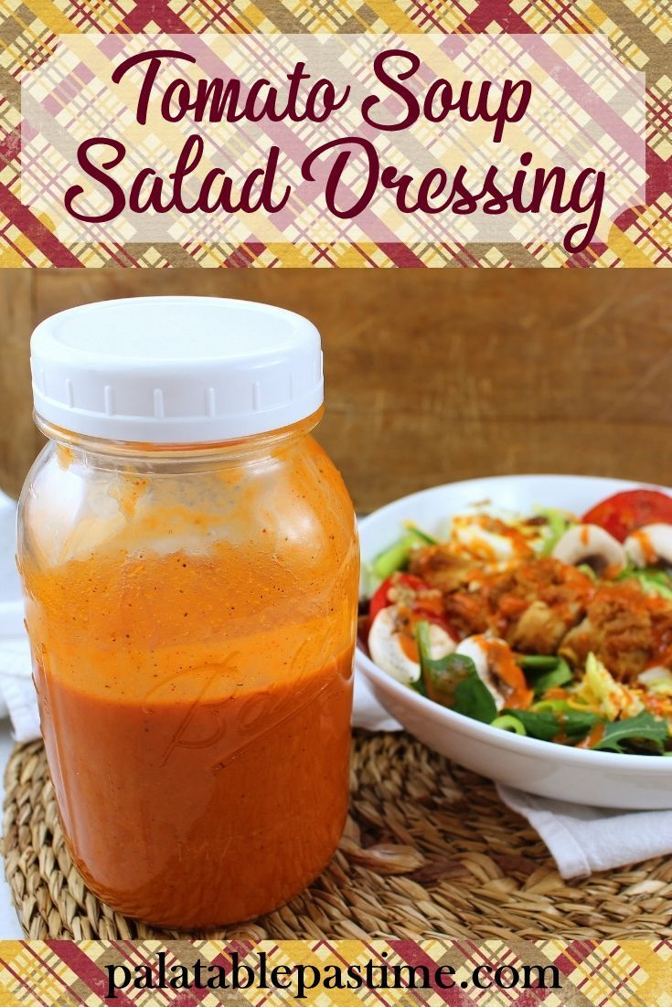 tomato soup salad dressing in a mason jar next to a bowl of salad on a woven placemat