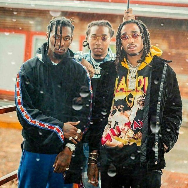 three young men standing in the snow with one holding an umbrella