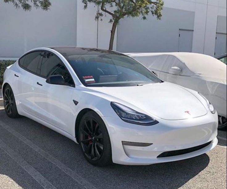 a white tesla model 3 parked in a parking lot