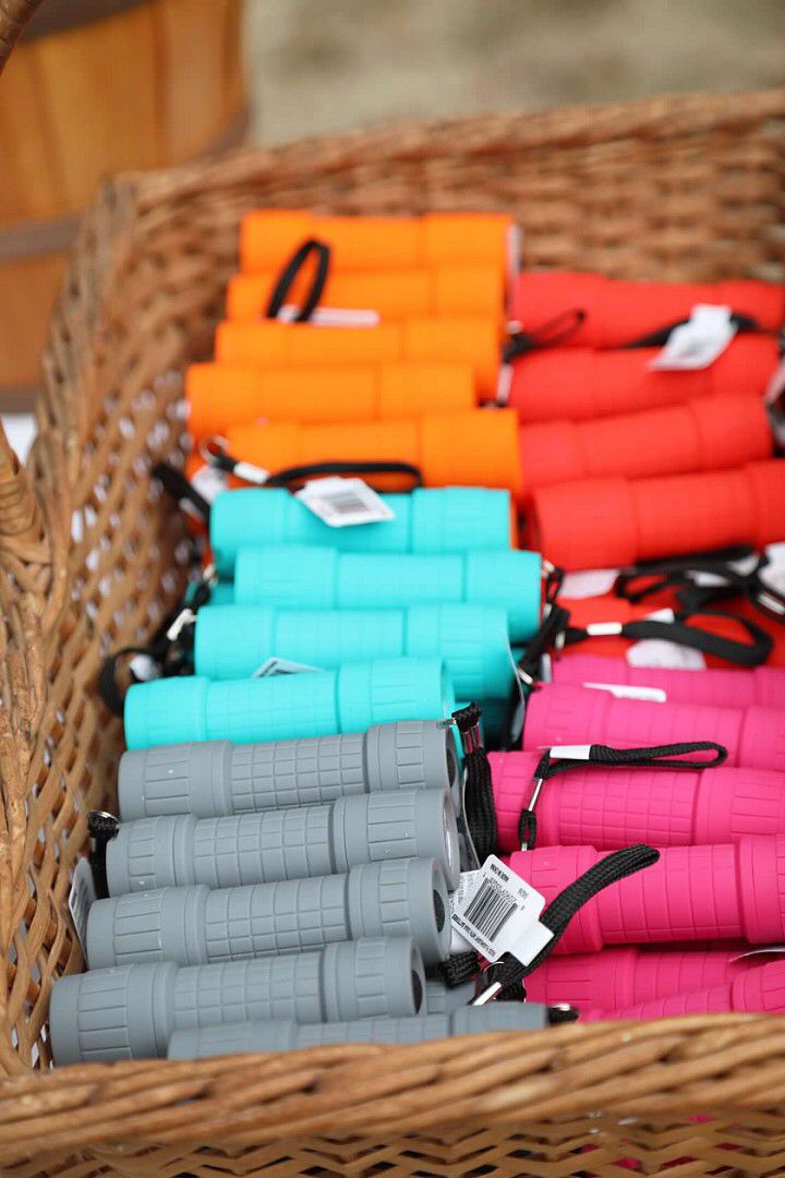 many different colors of umbrellas in a wicker basket on the floor with tags