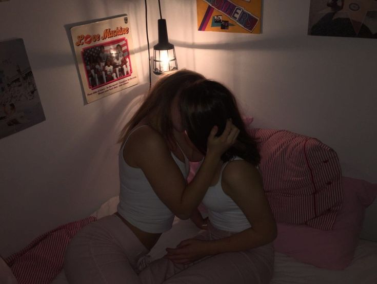 a woman sitting on top of a bed next to a lamp