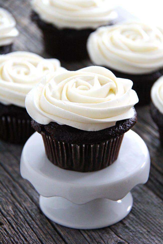 cupcakes with white frosting sitting on top of each other