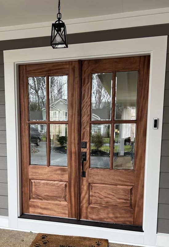 the front door to a house with two double doors and a rug on the floor