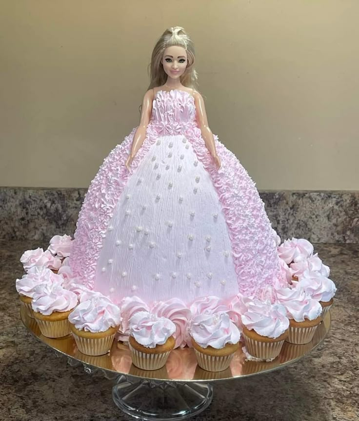 a barbie doll cake with cupcakes in the shape of a dress on top