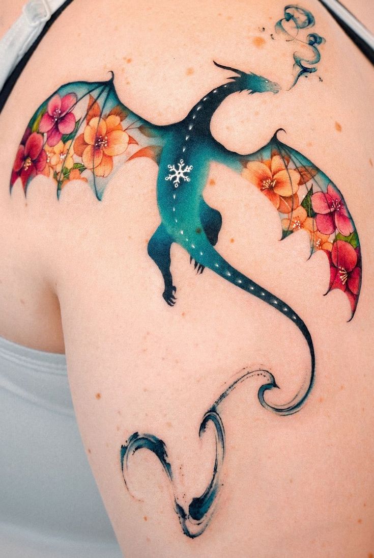 a woman's back with a dragon tattoo on her left shoulder and flowers painted on it