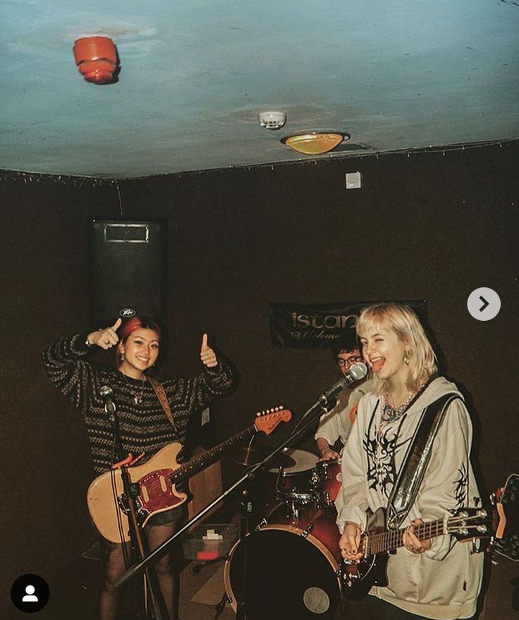 two women singing into microphones while playing guitars