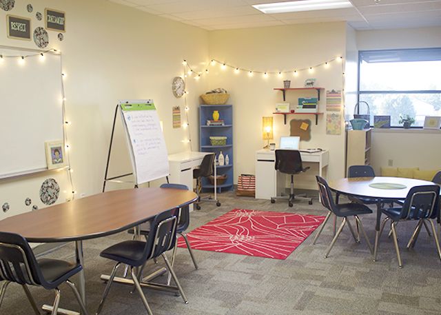 a classroom with tables, chairs and a whiteboard on the wall in front of it