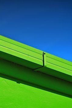 the top of a green building with blue skies in the backgroung area