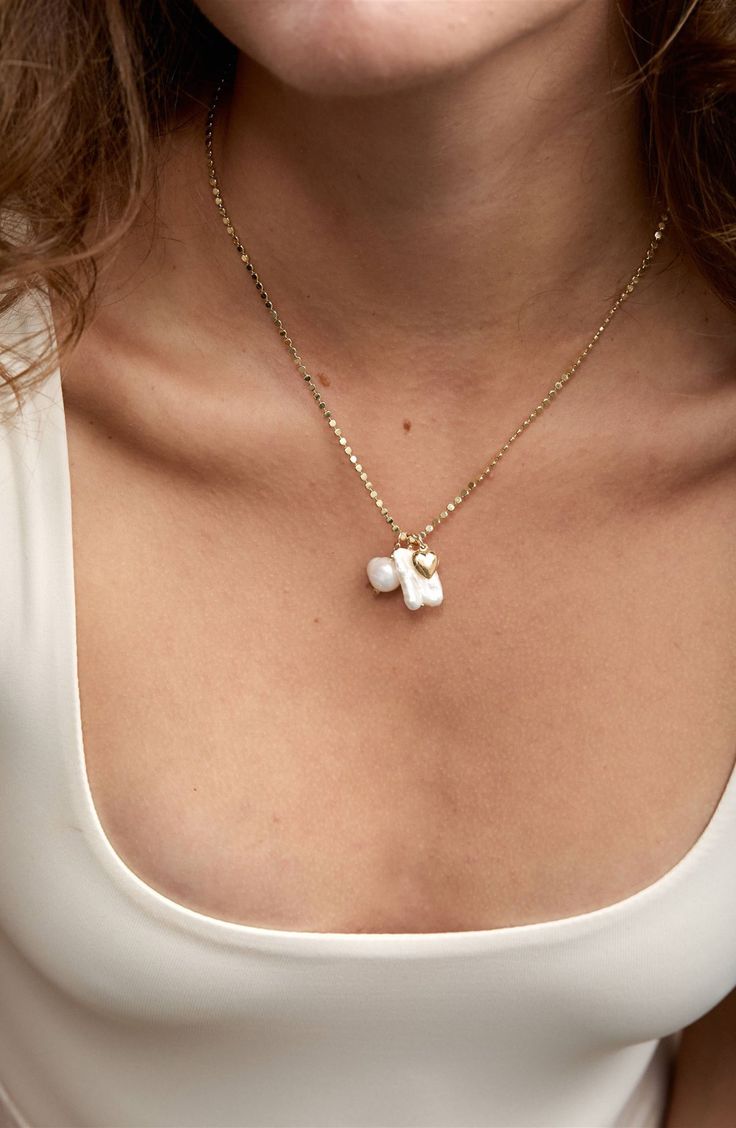 Handmade with a biwa pearl, an akoya pearl and heart charm dangling from a dainty chain, this necklace makes a lovely addition to your everyday look. 18" length Pearl size: 11–12mm 18k-gold plate/14k-gold fill/freshwater biwa pearl/freshwater akoya pearl Made in the USA Everyday White Pearl Chain Charm Necklace, Pearl Cable Chain Necklaces As Gift, Dainty White Pearl Pendant Charm Necklace, Dainty Pearl Charm Necklace For Everyday, Dainty Pearl Necklace With Pendant Charm, Dainty Drop Necklace With Pearl Charm, White Pearl Dangle Charm Necklaces, White Pearl Drop Pendant Charm Necklaces, Pearl Charm Pendant Necklaces