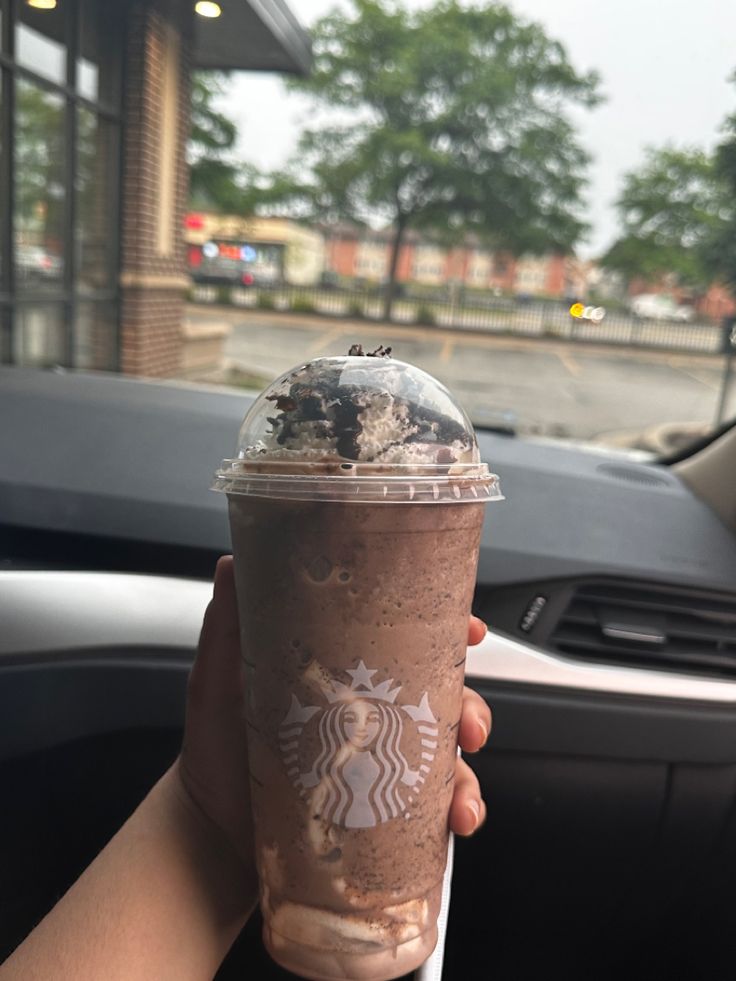 a person holding up a starbucks drink in their hand