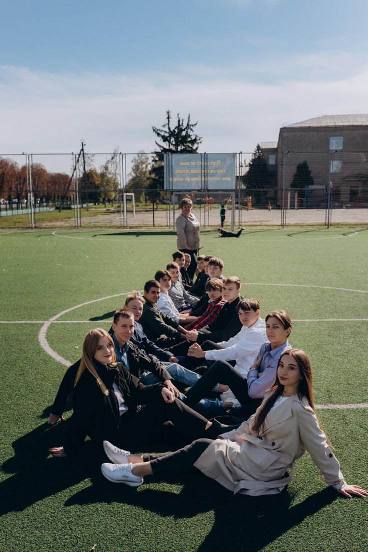 a group of young people sitting on top of a soccer field next to each other