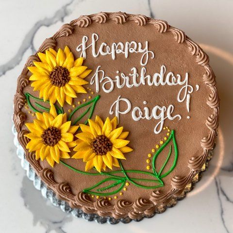 a birthday cake decorated with sunflowers and the words happy birthday pegie on it