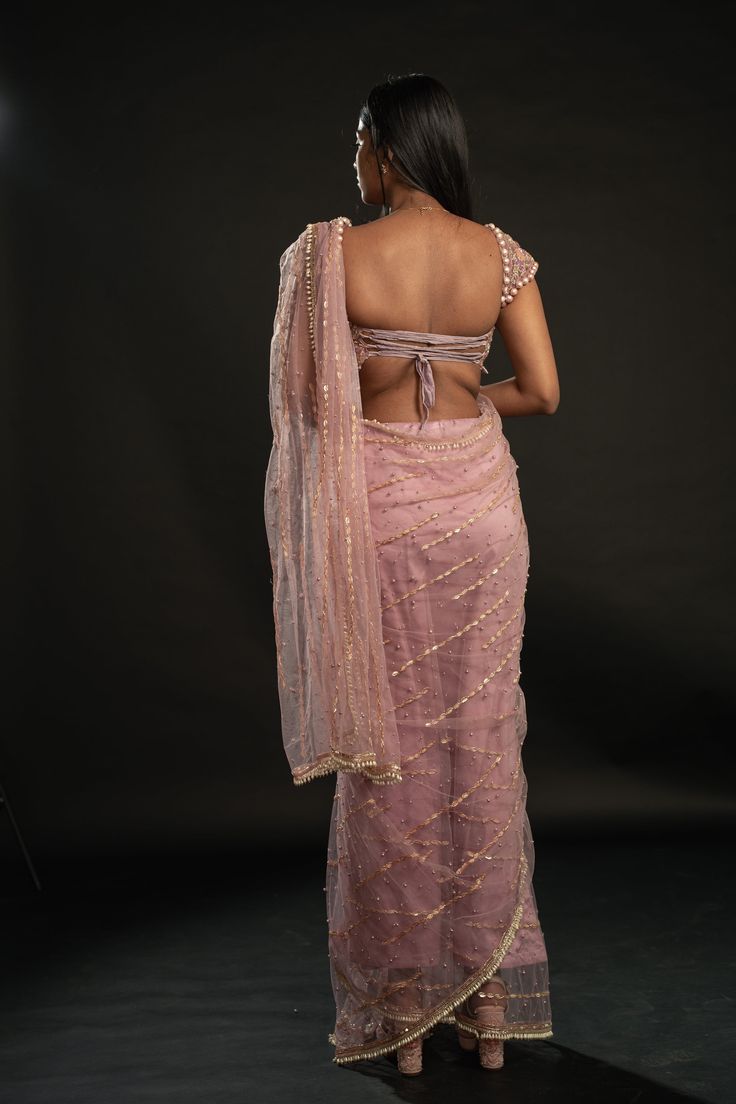 This dusty pink saree is a vision of elegance, crafted from Net fabric that glimmers with every movement. Paired with a Net blouse, the ensemble radiates sophistication and charm. The intricately hand-embroidered blouse adds a touch of glamour, making it perfect for a cocktail or reception, whether for the bride or her bridesmaids. With its timeless allure and delicate detailing, this saree is sure to captivate attention and leave a lasting impression on any special occasion.From Jigar & Nikita' Evening Chanderi Blouse Piece With Mirror Work, Fitted Chanderi Blouse Piece For Evening, Evening Chanderi Blouse Piece With Sheer Dupatta, Evening Tissue Silk Saree With Cutdana, Evening Cutdana Tissue Silk Saree, Pink Floor-length Blouse Piece With Sheer Dupatta, Evening Lehenga With Mirror Work In Tissue Silk, Evening Chanderi Pre-draped Saree With Pallu, Evening Pre-draped Chanderi Saree With Pallu