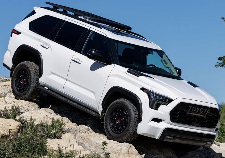 a white toyota suv is parked on some rocks