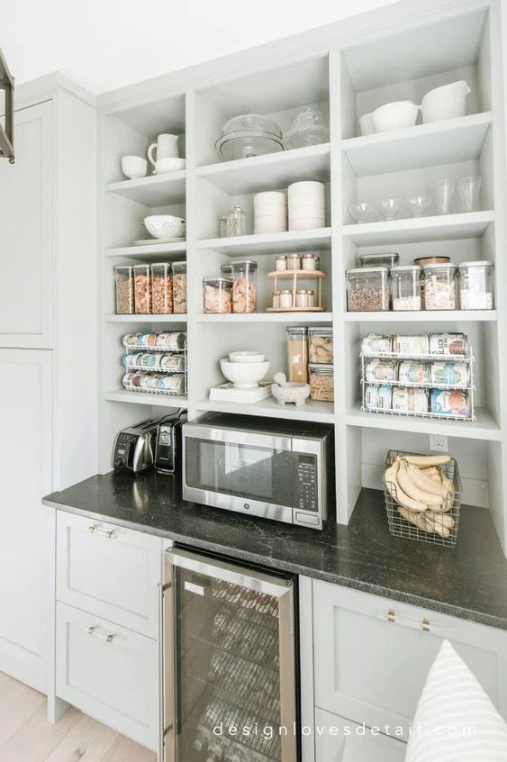 a kitchen with white cabinets and shelves filled with dishes on top of the countertop