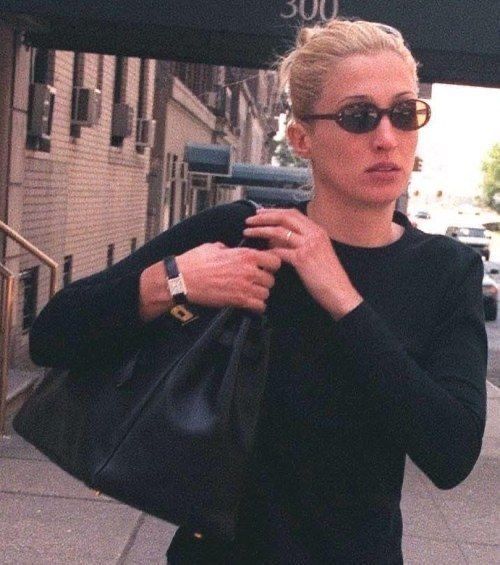 a woman walking down the street carrying a black purse