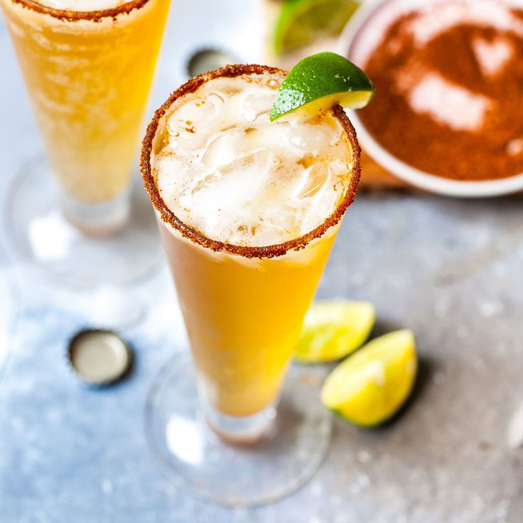 two glasses filled with drinks sitting on top of a table