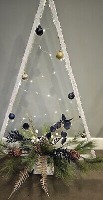 a christmas tree with lights and ornaments on it's branches in front of a wall