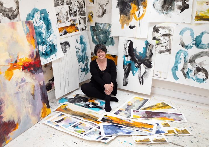 a woman sitting on the floor in front of paintings