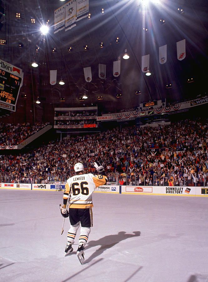 an ice hockey player is skating on the ice in front of a large crowd at night