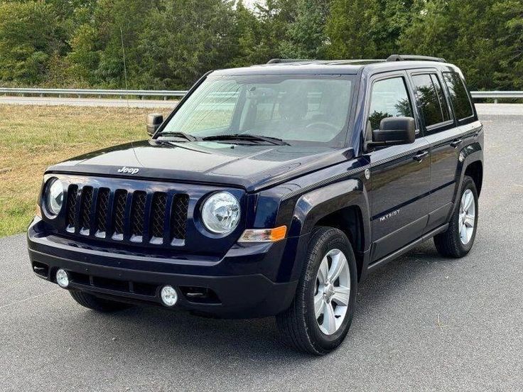 a blue jeep is parked on the side of the road in front of some trees