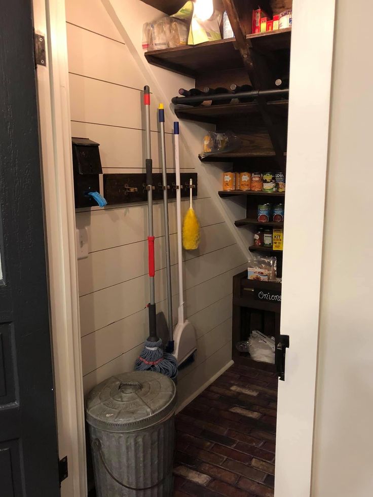 there is a bucket and mop on the floor in this small room with shelves