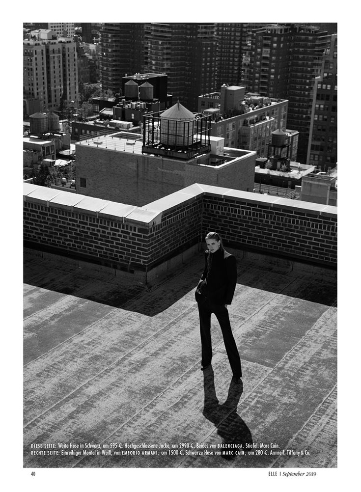 a man standing on top of a roof next to a tall cityscape with buildings in the background