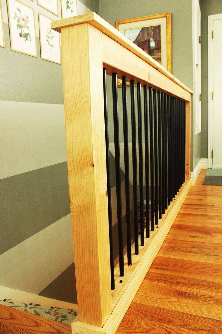 a wooden stair case with black bars on the bottom, and an image of a mirror above it