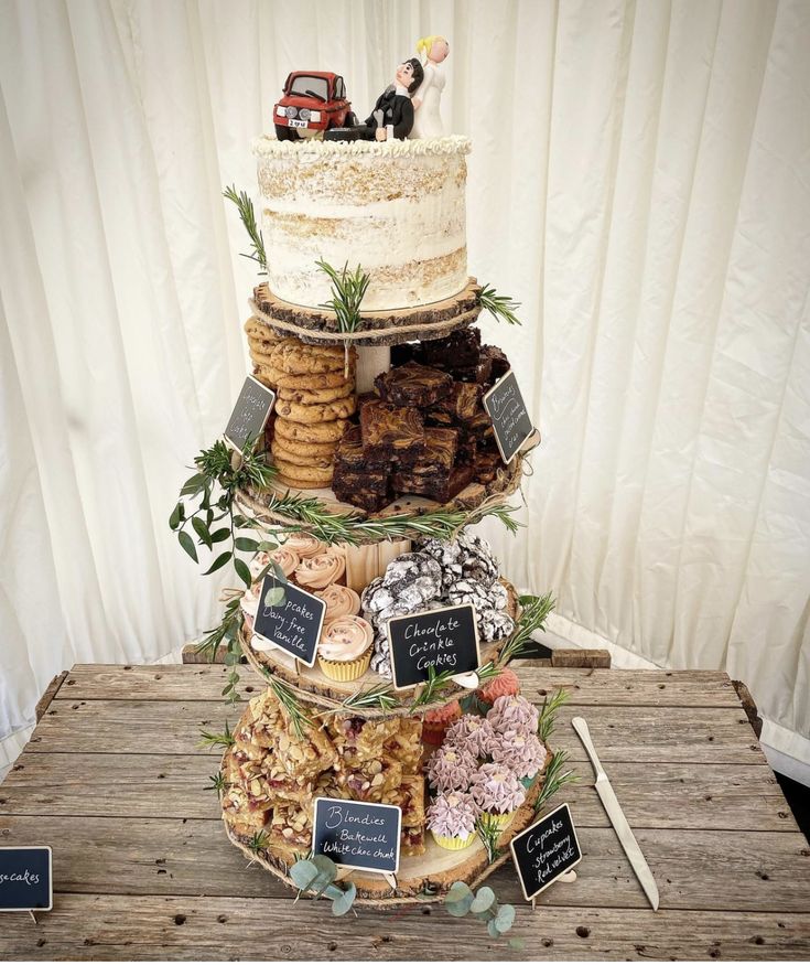 a three tiered cake on top of a wooden table with cookies and pastries