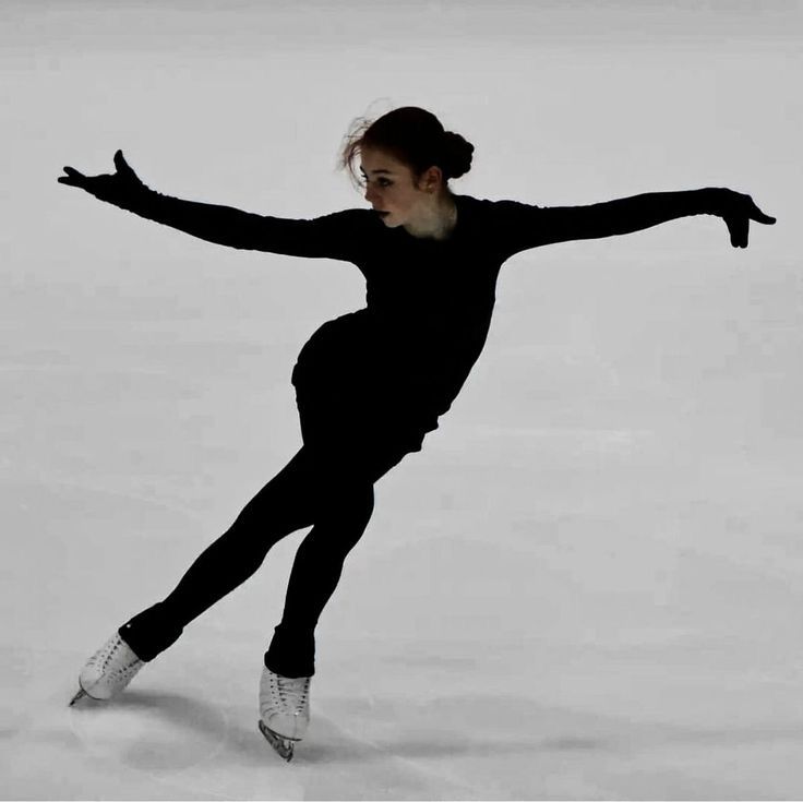 a woman skating on an ice rink in front of the camera with her arms outstretched