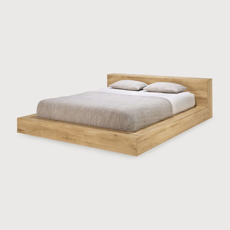 a bed that is made up and has two pillows on top of it, with the headboard turned down