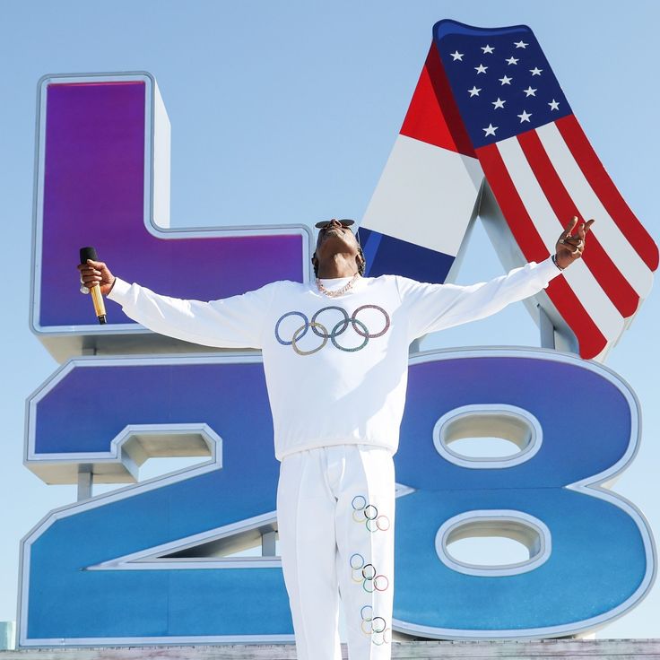 a man holding an olympic flag in front of a large sign with the number 28 on it