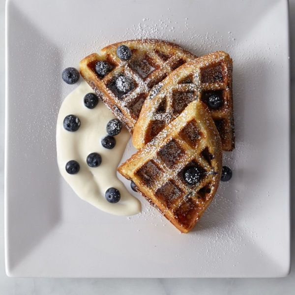 waffles with blueberries and cream on a white plate