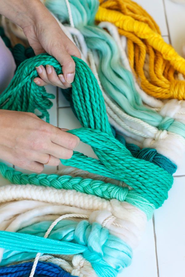 someone is tying rope on the floor with different colors and sizes in order to make it look like they are weaving