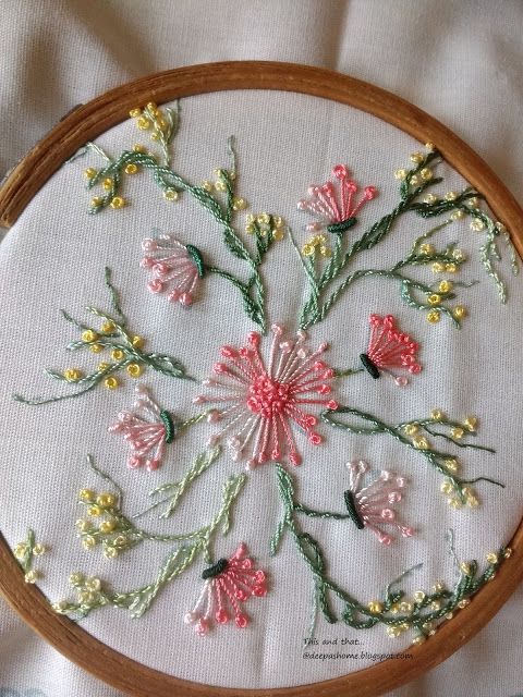 a close up of a embroidery on a piece of cloth in a wooden hoop with flowers