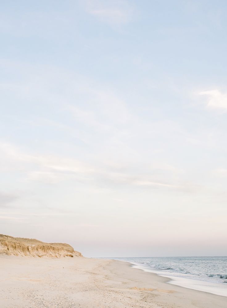 an empty beach with the ocean in the background