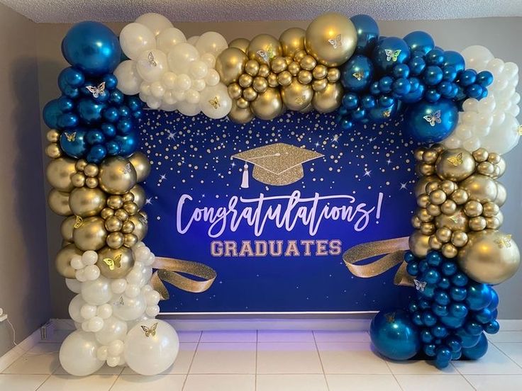 an arch made out of balloons and confetti graduation decorations on the wall behind it