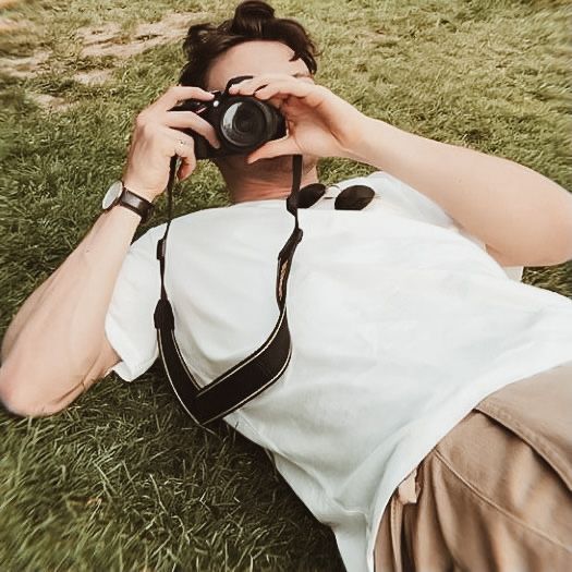 a man laying in the grass with a camera