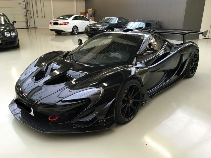 a black sports car parked in a garage next to two other cars on the floor