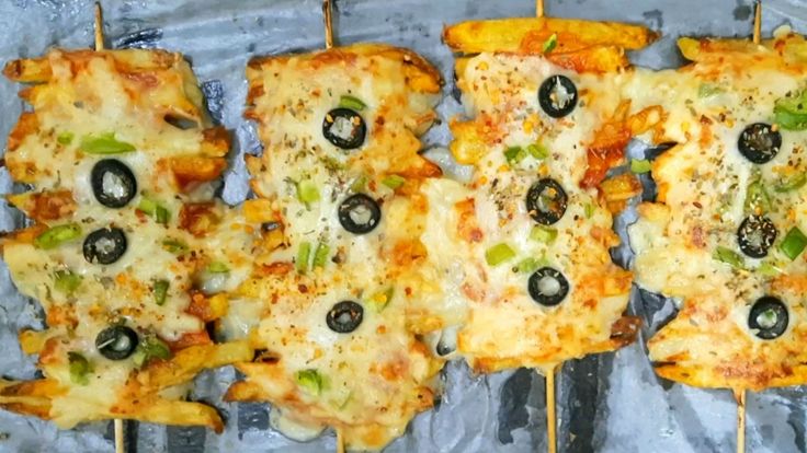 several pieces of pizza on skewers with olives and cheese, sitting on tin foil